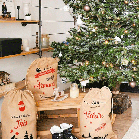 Hottes de Noël personnalisées "Armand", "Inès" et "Victoire" sous un sapin de Noël - MonSacdeNoel